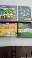 Four boxed board games: Tribond, The Man Game, Cadoo, Word Thief arranged on table