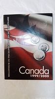 Front cover of the booklet displaying the Canadian 1999/2000 millennium 25 cent coin collection with Canadian flag background