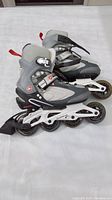 Side view of gray and black Airwalk in line skates showing four wheels on white frame and buckle fastening.