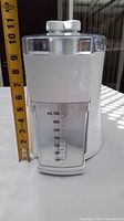 Front view of Kenmore juice extractor showing juice container with measurement markings and ruler for size reference.