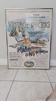 Full view of the framed vintage racing festival poster showing colorful illustrations and event information.