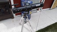 Front side view of Bushnell telescope on aluminum tripod with original box in background