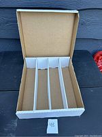 Photo of the open cardboard card organizer showing four compartments inside and the foldable lid.