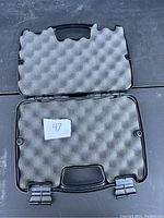 Black hard plastic protective case opened to show foam interior padding on both lid and base.