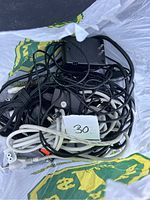 Photo showing a pile of mixed cords and power adapters inside a plastic bag with a paper label '30' on top.