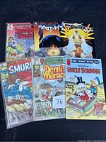 Photo of 6 vintage comic books including Disney and Marvel characters in protective plastic sleeves on dark surface.