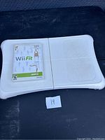 Photo of the Wii Fit Balance Board and the Wii Fit game disc in case placed on board.