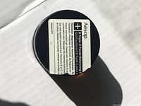 Top view of sealed black jar of Aesop Triple C Facial Balancing Gel showing product label on lid.