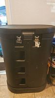 Black hard commercial rolling case with handle and metal latches for secure transport of disassembled trade show display components.