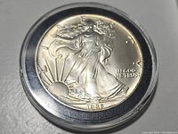 Front side of 1986 Liberty silver coin showing Walking Liberty design with date 1986 and inscriptions.