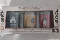 Box showing the three candles visibly through the plastic window with scent names and weights.