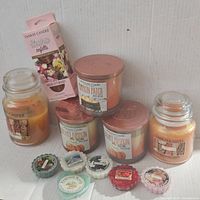 Wide view of all candles, wax melts and oil refill box arranged against white background.