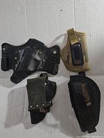 Four assorted holsters laid flat showing fronts and attachment mechanisms.