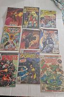 Photo showing 9 vintage Marvel comic books laid out on a white surface including Marvel Fanfare, Marvel Greatest Comics, Marvel Saga titles
