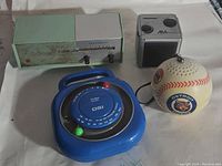 Lot showing four vintage transistor radios together on a table: green Panasonic Caravan, silver AM Mode cube radio, blue DSI round radio, and baseball-shaped Detroit Tigers radio.