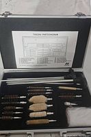 Open case showing firearm cleaning kit contents including rods, brushes, and cotton mops along with parts diagram.