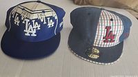Both LA Dodgers New Era caps laid side by side, showing front and side design details.