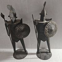 Front view of both vintage Lobeco tin knights standing side by side, showing shield embossing and plume details on helmets.