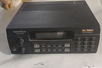 Front view of Radio Shack Pro-2052 scanner showing volume, squelch knobs, numeric keypad, display screen, and function buttons.