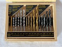 Wooden case with drill bits inside arranged in three compartments: tungsten tipped masonry drill bits, titanium coated metal drill bits, and precision read point wood drill bits. The size and type labels are clearly visible on the case's interior.