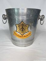 Front view of a silver metal ice bucket with Veuve Clicquot Ponsardin champagne label, showing scratches and dings.