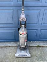Front view of Hoover WindTunnel T-Series upright vacuum cleaner showing clear dirt bin, handle, and base with brush area.