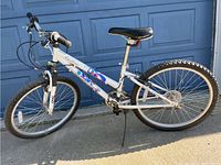 Side view of the full white Nakamura bicycle showing the frame, wheels, pedals, seat, and handlebar with some missing grip rubber.