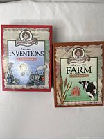 Front view of the two card game boxes: Famous Inventions and Life on the Farm by Professor Noggins.