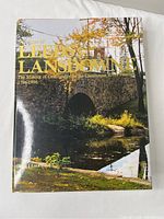 Front cover of the book showing a stone bridge over a river with trees and foliage, title text in yellow.