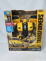 Front view of Transformers Power Charge Bumblebee figure in original box, showing yellow robot with open car doors and packaging text.