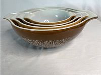 Side view of the four nested Pyrex Woodland Cinderella bowls showing the brown and beige color scheme and floral geometric pattern around the sides.