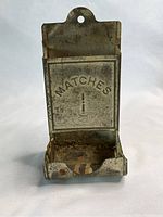 Front view of the vintage tin match holder showing 'MATCHES' embossed and visible rust and wear.