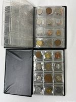 Top view of two black coin holder books open flat showing mixed coins in plastic sleeves, light and dark toned coins visible.