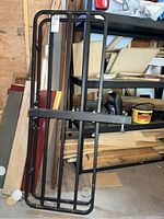 Haul Master metal cargo carrier viewed from side showing long frame with clamps and bars standing against shelving in a garage.