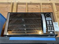 Front view of Hamilton Beach microwave showing door and stainless steel handle with mesh screen window.