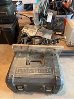 Delta miter saw, Craftsman floor jack, Black & Decker bench grinder, and other assorted tools visible in garage environment.