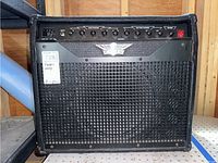 Front view of Raven RG60 amplifier showing metal grille with Raven logo, control panel at top, and on/off switch. Visible wear on edges and corners.