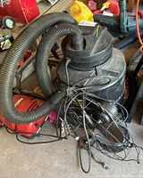 Photo of vintage Westinghouse fan and Genie shop vacuum in garage setting, showing fan blades and protective wire cage along with vacuum hose.