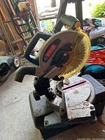 Ryobi miter saw close-up showing base, blade guard, and handle with visible wear and dirt.