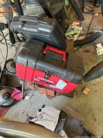 Red and black Craftsman toolbox on top of an old metal vise base and other workshop tools.