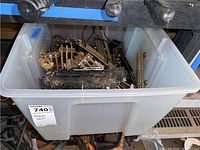 Top view of a plastic bin containing a black Lionel toy train engine and multiple rusted metal track pieces including switches.