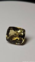 Close-up photo of 11.70ct champagne colored cushion cut citrine gemstone showing facets and high luster.