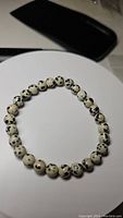 Dalmatian jasper beaded stretchy bracelet laid flat on a white surface showing bead color and pattern.