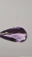 Close-up photo of the pear-shaped pink to purple amethyst gemstone with checkerboard faceting showing color and clarity.