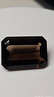 Front view of a large emerald cut smokey quartz gemstone showing deep brown color and facets.