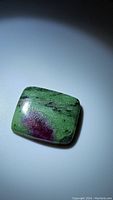 Square cabochon cut natural ruby zoisite gemstone with green, red, and black coloring.
