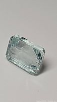 Close-up front angle of untreated emerald cut aquamarine showing color and facets