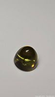 Close-up photo of deep yellow lemon citrine bullet cabochon gemstone showing glossy finish and smooth surface.