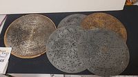Five antique Regina music box metal discs displayed flat, showing varying degrees of patina and punched holes over surface.