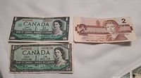 Two Canadian one dollar bills and one Canadian two dollar bill front side with portraits of Queen Elizabeth II.